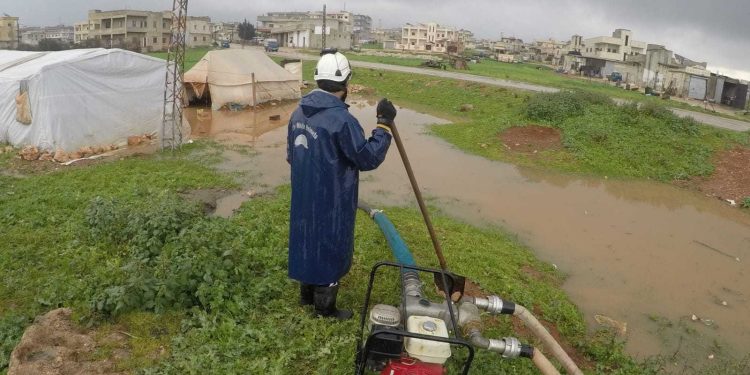 عنصر للدفاع المدني السوري في مخيم المغسلة ببلدة رام حمدان شمالي إدلب بعد اقتحام السيول للخيام آذار 2024 (الدفاع المدني السوري)