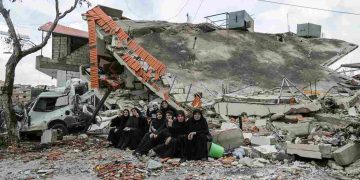 سكان قرية عيتا الشعب بجنوب لبنان يقفون لالتقاط صورة أمام منزل دمرته نيران إسرائيلية 9 أبريل 2024(ا ف ب)
